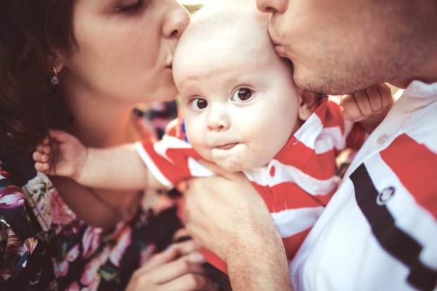 boy-looks-funny-while-parents-kiss-his-head.jpg