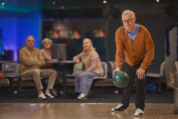 full-length-portrait-active-senior-man-playing-bowling-with-group-friends-background-copy-space.jpg